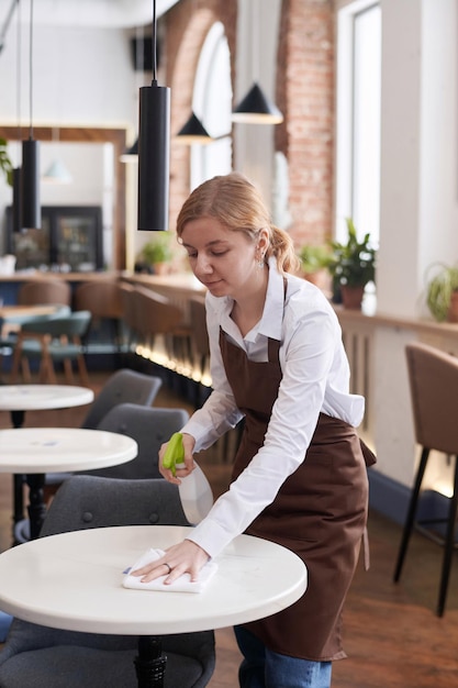 Une jeune serveuse nettoie la table.