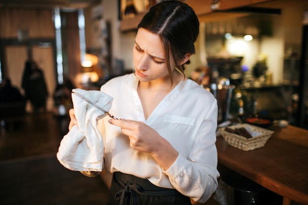 Jeune serveuse occupée au bar et essuyer le couteau