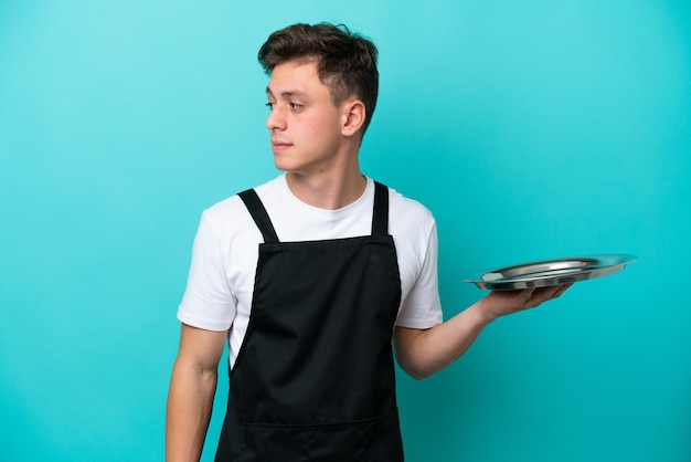 Jeune serveuse avec plateau isolé sur fond bleu regardant sur le côté