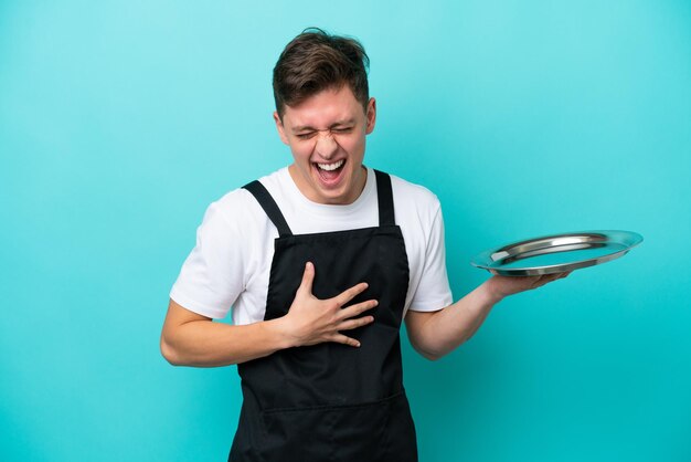 Jeune serveuse avec plateau isolé sur fond bleu souriant beaucoup