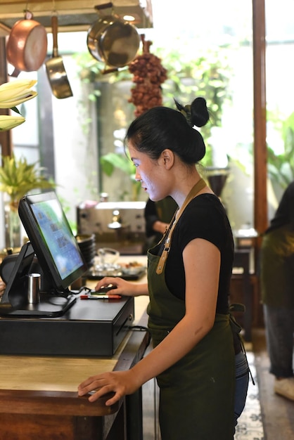 Jeune serveuse vietnamienne servant un client à la caisse au café