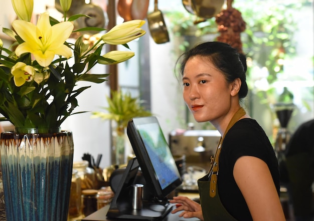 Jeune serveuse vietnamienne travaillant avec une machine de paiement