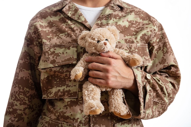 Jeune soldat tenant un ours en peluche debout sur fond blanc