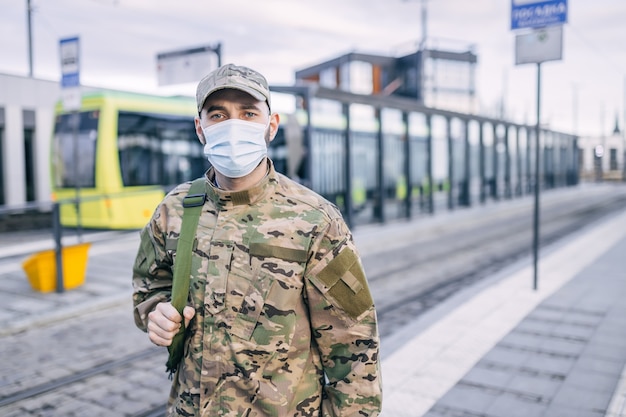 Un jeune soldat en tenue de camouflage et un masque de protection dans la rue