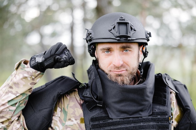 Un jeune soldat en uniforme et gilet tactique travaille dans la forêt et se prépare à l'action dans une base forestière temporaire Un homme fait des travaux de déminage du territoire