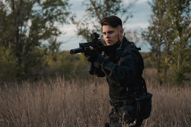 Jeune soldat en uniforme noir visant un fusil d'assaut