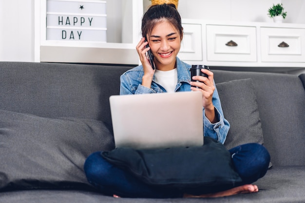 Jeune souriante heureuse belle femme asiatique se détendre à l'aide d'un ordinateur portable travaillant et réunion de vidéoconférence à la maison.