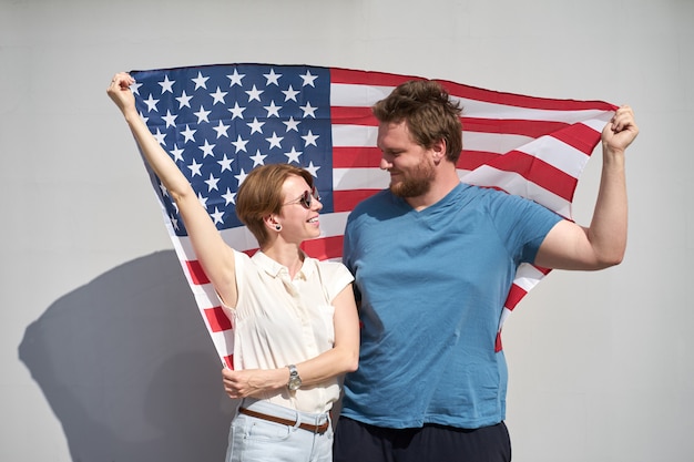 Jeune, sourire, caucasien, couple américain, tenir, USA, drapeau, derrière, et, regarder, autre