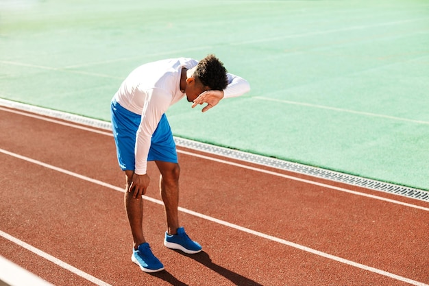 Un jeune sportif afro-américain épuisé s'est arrêté pendant la course sur l'hippodrome du stade de la ville