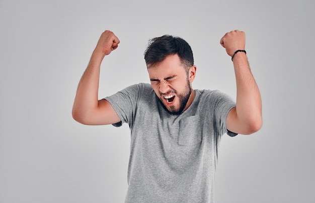 Jeune sportif caucasien émotif réussi avec des cheveux noirs criant Oui et levant les poings serrés en l'air, se sentant excité. Personnes, succès, triomphe, victoire, victoire et célébration