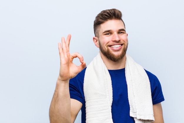 Jeune sportif caucasien avec une serviette joyeux et confiant montrant un geste correct.