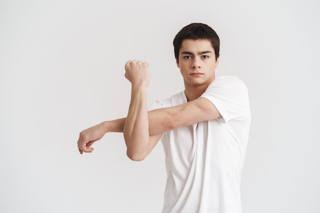 Jeune sportif confiant faisant des exercices d'étirement isolés sur un mur blanc