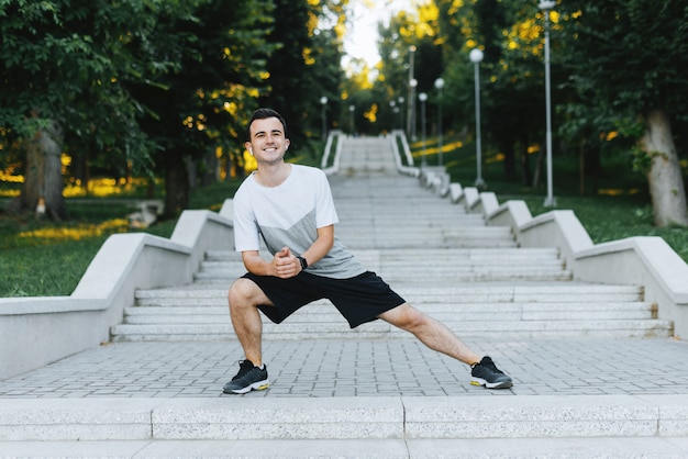 Jeune sportif heureux je souriant à la caméra et faire du sport dans le parc.