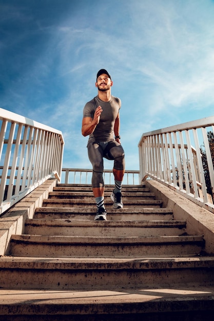 Jeune sportif musclé qui descend les escaliers du pont.