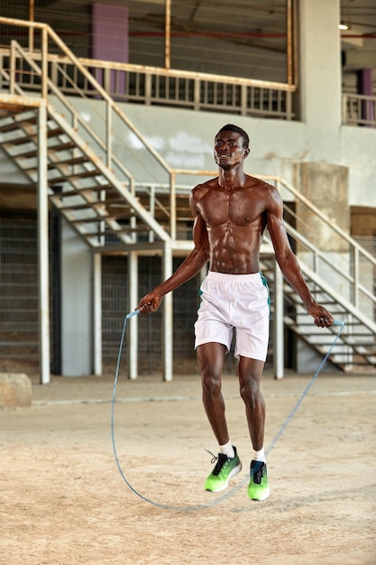 Jeune sportif noir s'entraînant avec une corde à sauter à l'extérieur