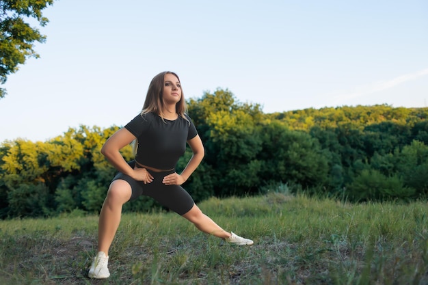 Jeune sportive garde ses mains sur sa ceinture et effectue des squats sur une jambe