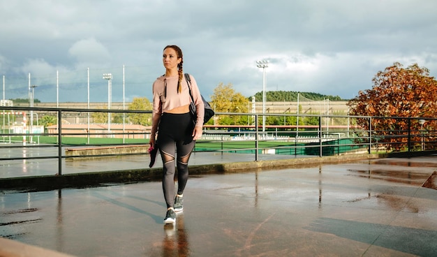 Jeune sportive avec sac de sport et chaussures de sport marchant pour aller à l'entraînement