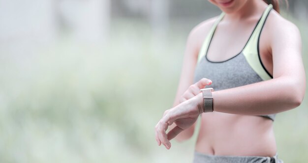 Jeune sportive touchant sur l'écran de la smartwatch dans l'activité sportive active. Copiez l'espace.