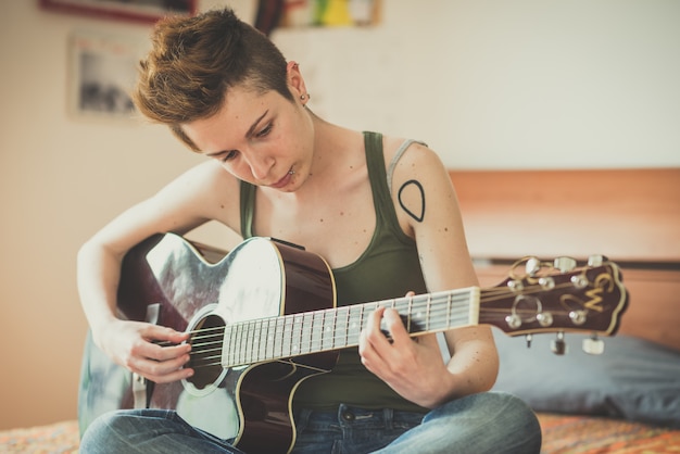 jeune style de cheveux élégant femme jouant de la guitare