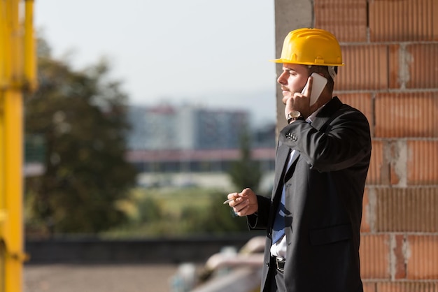 Jeune superviseur parlant sur téléphone portable et fumant un cigare