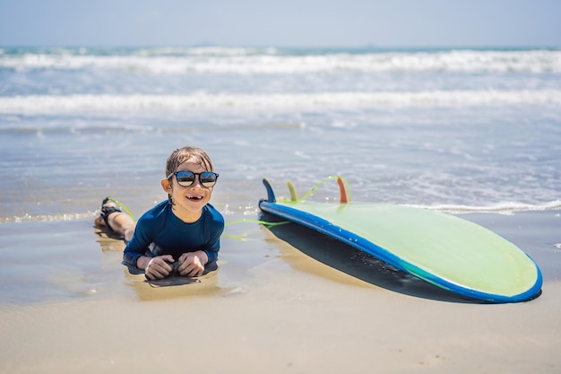 Jeune surfeur heureux jeune garçon à la plage avec planche de surf