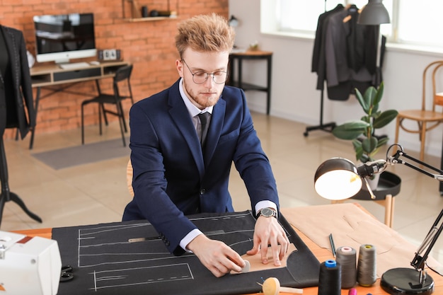 Jeune tailleur travaillant à table en atelier