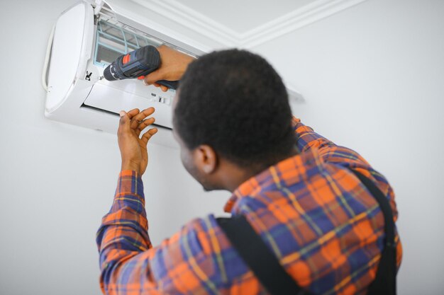 Photo jeune technicien africain réparant un climatiseur