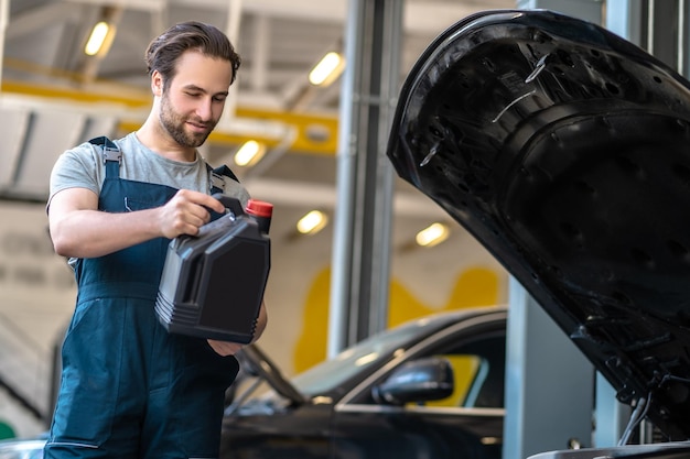 Jeune technicien automobile effectuant la vidange d'huile moteur