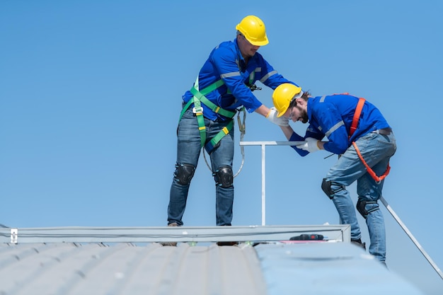 Un jeune technicien stagiaire travaillant sur des panneaux solaires a peur des hauteurs avec des ingénieurs seniors