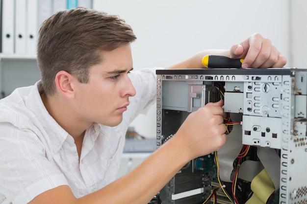 Jeune technicien travaillant sur un ordinateur cassé