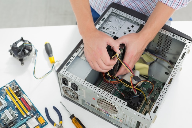 Jeune technicien travaillant sur un ordinateur cassé