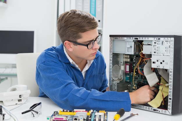 Jeune technicien travaillant sur un ordinateur cassé