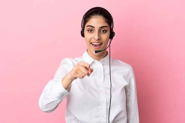 Jeune télévendeur sur fond isolé surpris et pointant vers l'avant