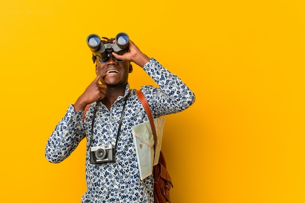 Jeune touriste africain debout tenant une jumelle