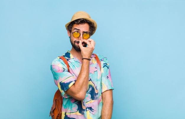 Jeune touriste barbu se sentant dégoûté, tenant le nez pour éviter de sentir une odeur nauséabonde et désagréable