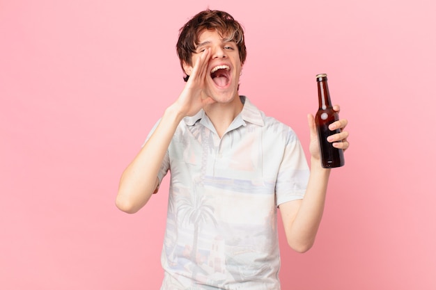 Jeune touriste avec une bière se sentant heureux avec un grand cri avec les mains à côté de la bouche