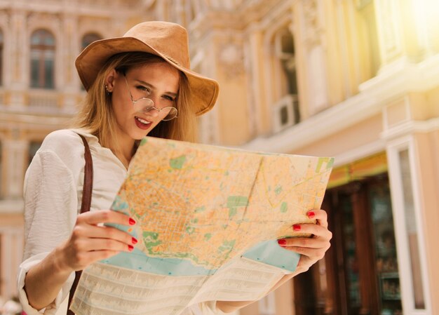 Jeune touriste blonde à la recherche du plan de la ville l'ancienne architecture urbaine