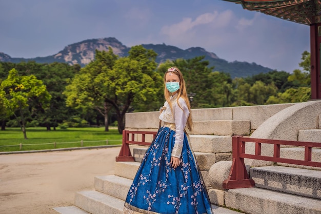 Jeune touriste caucasienne en masque médical dans le hanbok national korean dresstravel en corée