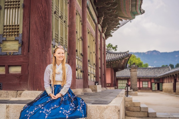 Jeune touriste caucasienne en robe coréenne nationale hanbok au palais coréen Concept de voyage en Corée Vêtements coréens nationaux Divertissement pour les touristes essayant des vêtements coréens nationaux