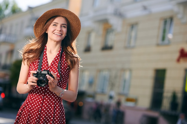 Jeune touriste femme souriante se promène dans la ville en été et tient la caméra