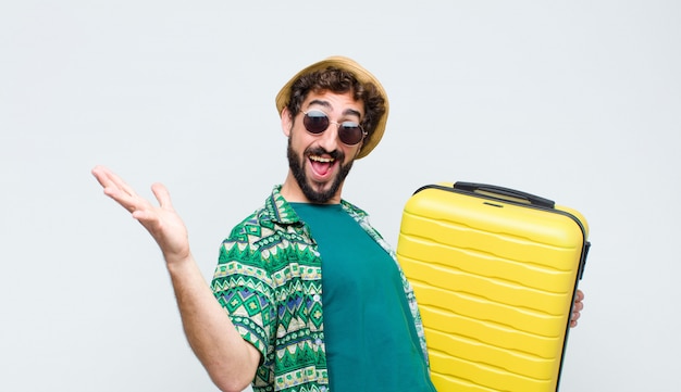 Jeune touriste homme avec une valise sur mur blanc. concept de voyage