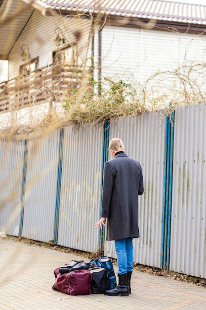 jeune touriste masculin dans un manteau avec une valise d'arrivée ou de départ dans le parc à la recherche de géolocalisation dans le téléphone.