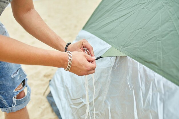 Un jeune touriste met une tente verte sur la côte de la plage L'homme installe un camp lors d'une randonnée