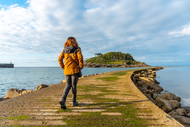 Un jeune touriste sur la passerelle pour se rendre à l'île San Nicolas à marée basse depuis la plage d'Isuntza à Lekeitio, Pays Basque