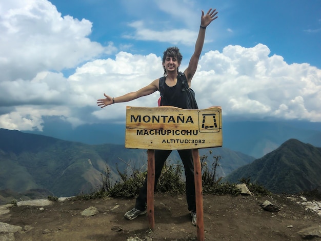 Jeune touriste posant à côté d'un panneau indiquant l'altitude de la montagne Machu Picchu.