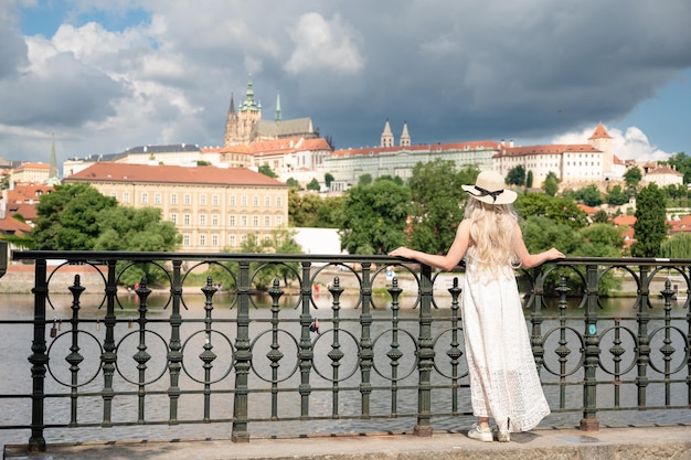 Une jeune touriste posant près de la clôture du remblai de la Vltava dans le centre historique de Prague.