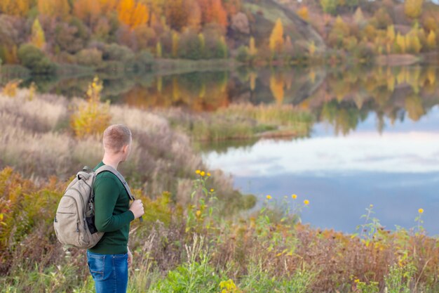 Jeune touriste avec sac à dos près du lac d'automne