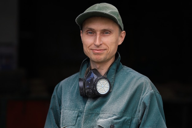 Jeune travailleur dans un uniforme vert et avec un respirateur