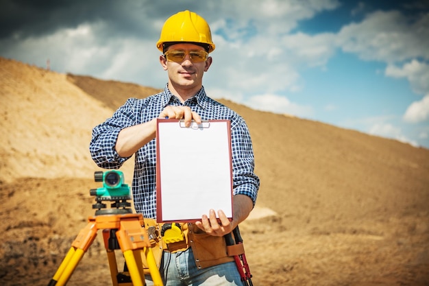 Un jeune travailleur faisant la démonstration d'un presse-papiers sur un chantier de construction