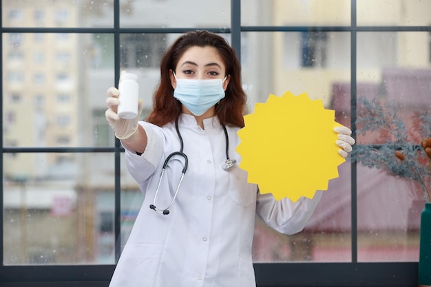 Jeune travailleur de la santé en masque tenant une bulle d'idée et de la drogue au bureau Photo de haute qualité